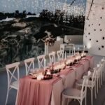 White cross-back chairs at an outdoor wedding reception.