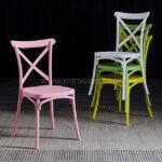 Rainbow stack of cross-back chairs in five vibrant colors.