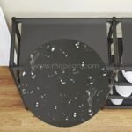A close-up of the black shoe rack’s top shelf, showing its water-resistant surface with visible water droplets.