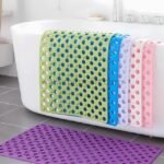 Colorful non-slip massage bath mats in green, blue, purple, and pink placed inside a bathtub.
