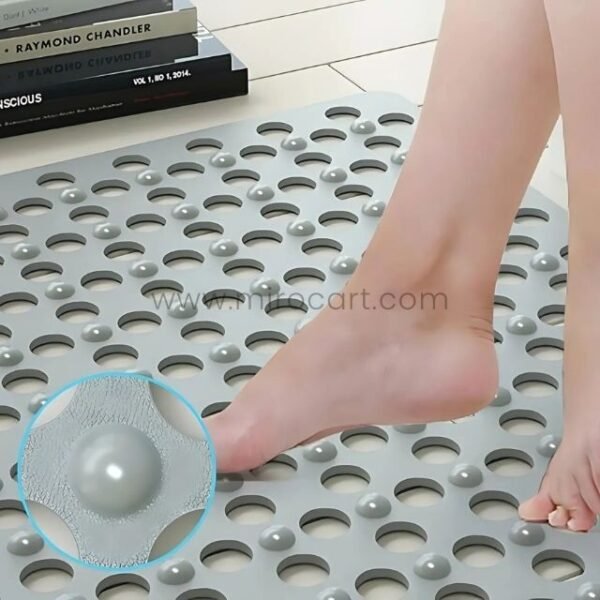 Close-up of a foot stepping onto a gray non-slip massage bath mat with raised bumps.