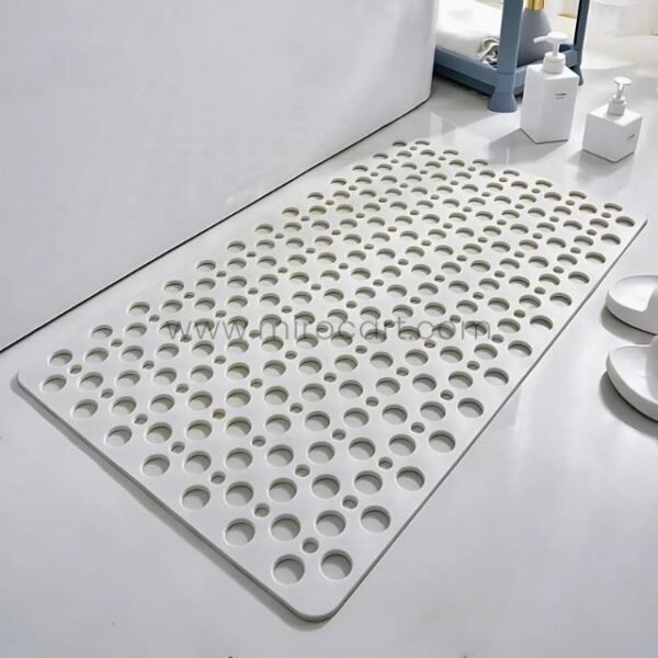 White non-slip massage bath mat placed next to a bathtub on clean tile flooring.