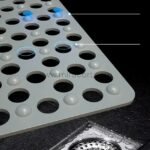 Close-up of a gray non-slip massage bath mat showing holes and suction cups.