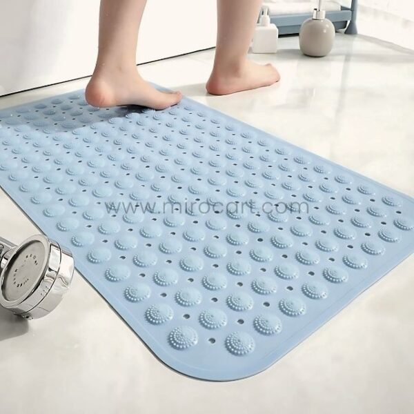A woman stepping onto a light blue non-slip bathtub mat placed near a shower on tiled flooring.