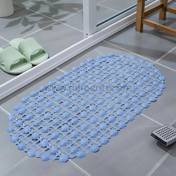 A blue non-slip shower mat with circular patterns, placed on a tiled floor near a shower drain.