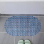 A bright blue non-slip shower mat with circular patterns, placed on a tiled floor near a bathtub.
