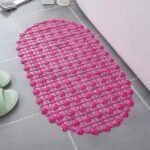 A vibrant pink non-slip shower mat with heart-shaped patterns, placed on a tiled floor near a bathtub.
