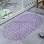A soft purple non-slip shower mat with circular patterns, positioned on a tiled floor near a shower drain.