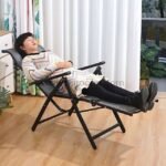 A woman reclining on a zero-gravity lounge chair with eyes closed, relaxing indoors during daylight.