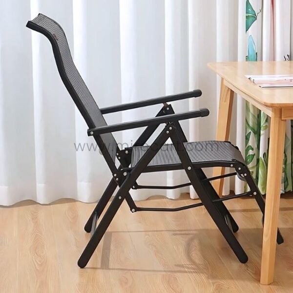 A premium zero-gravity lounge chair placed beside a wooden desk with a laptop, notebook, and pen nearby.