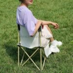 Woman relaxing in purple shirt on camping chair.