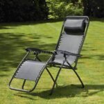 A modern black zero-gravity lounger sits nestled in a vibrant garden, surrounded by swaying trees and dappled sunlight.