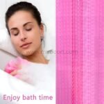 Woman relaxing in a bathtub with a pink textured 3D shower curtain creating a cozy, stylish backdrop.