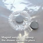 Close-up of a magnet weight at the bottom of a transparent shower curtain.