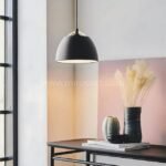 Sleek black Fjord Halo pendant light casts a warm ambient glow over a minimalist console in a modern living space.