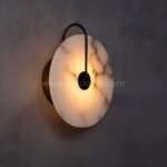 Black-framed Moonlit Alabaster Wall Light glowing warmly against a deep-toned wall.