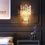 Crystal Cascade Wall Light glowing above a plush bed with layered linens and ambient tones.