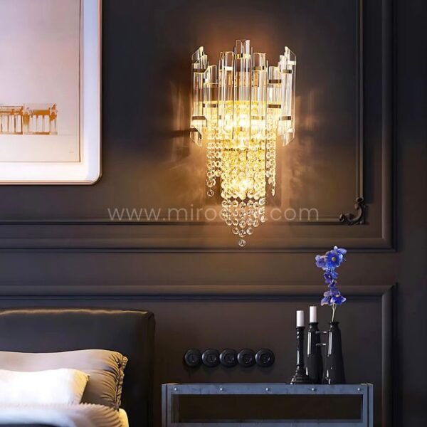 Crystal Cascade Wall Light glowing above a plush bed with layered linens and ambient tones.