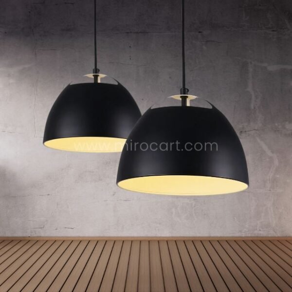 Two black Fjord Halo pendant lights with gold interiors glow warmly against a concrete wall in an industrial-style space.