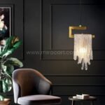 A single Flowing Waterfall Pendant Light hovers like a jewel over a plush armchair, its crystals whispering luxury against dark walls and lush greenery.