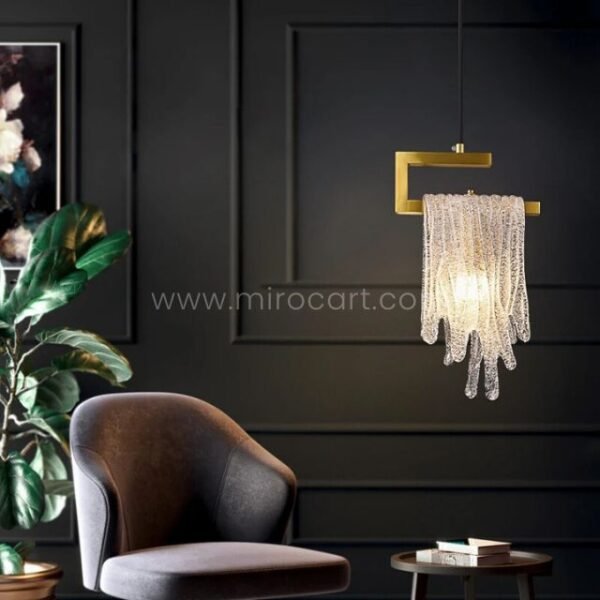 A single Flowing Waterfall Pendant Light hovers like a jewel over a plush armchair, its crystals whispering luxury against dark walls and lush greenery.