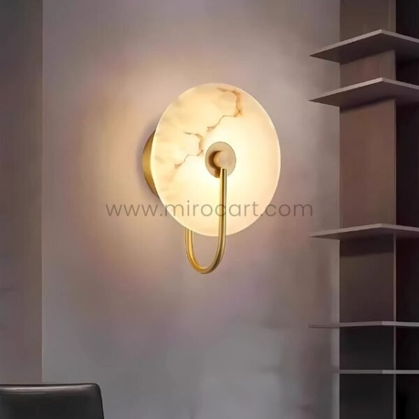 Gold-framed Moonlit Alabaster Wall Light mounted near modern shelving, exuding warm elegance.