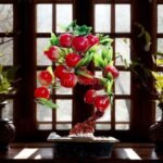 Graceful Chinese apple tree displayed indoors on a dark wooden stand next to a window with soft daylight highlighting its detailed branches and fruit.