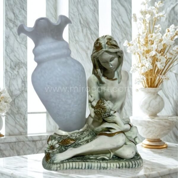 A handcrafted mother-child figurine in soft gray tones rests beside an opaline glass vase with a flared top, adding warmth and gentle texture to a minimalist setup.