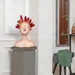 The Innocent Flame Resin Sculpture centered on a pedestal in a sleek, modern room with minimalist style.