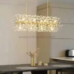 Luxury gold bar chandelier with cascading crystals glowing above a sleek modern dining setup.