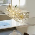 Gold bar chandelier with crystal branches sparkling above a minimalist kitchen island.