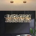 Luxury gold bar chandelier glowing against matte black wall panels.