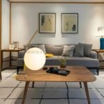 Minimalist gold sphere table lamp on a wooden side table in a cozy lounge setup.