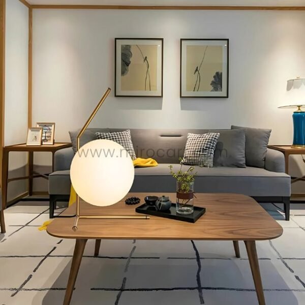 Minimalist gold sphere table lamp on a wooden side table in a cozy lounge setup.