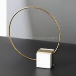 Minimalist Golden Ring Sculpture with gold ring and white marble base in a modern interior.