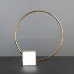 Minimalist Golden Ring Sculpture in a neutral black-and-white space.