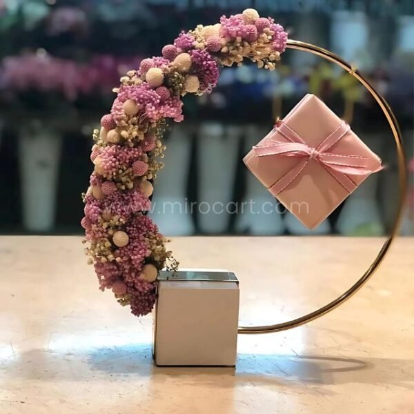 Golden ring sculpture decorated with fresh flowers and a small gift box.
