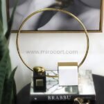 Minimalist Golden Ring Sculpture used to display books and decor pieces.