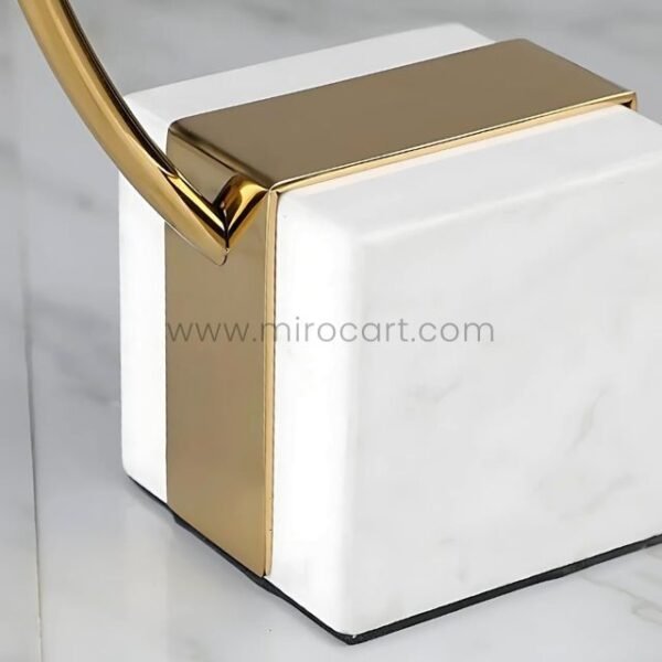 Close-up of white marble base with slim gold accent on sculpture.