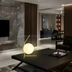 Minimalist gold sphere table lamp on a modern coffee table in a sleek living room.