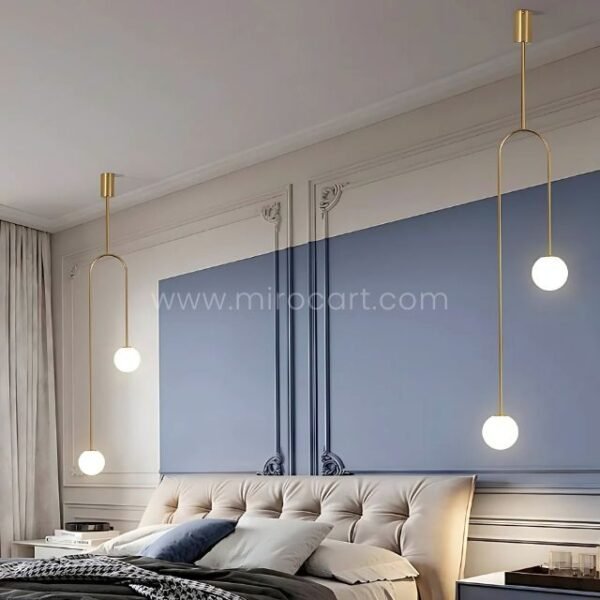 Gold modern arc pendant lights in a tranquil blue-gray bedroom.