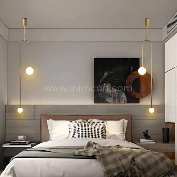 Twin gold modern arc pendant lights above a bed for symmetrical bedroom lighting.