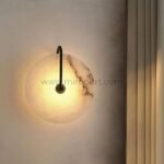 Moonlit Alabaster Wall Light with black metal frame on a soft wall, casting a tranquil glow.