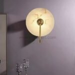 Gold-framed alabaster light casting a glow against a wall with crystal accents.