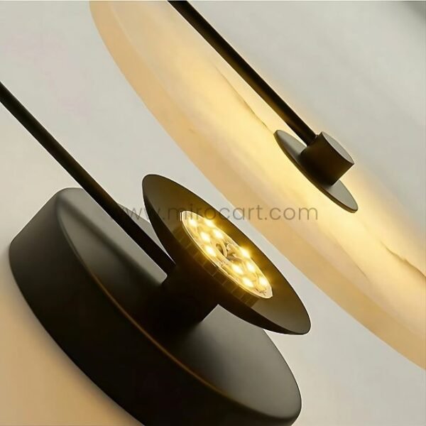 Contemporary LED wall light with black base and warm glow, mounted on a neutral wall.