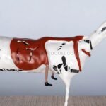 Side view of Shattered Ride sculpture, featuring its spiraled legs and vivid red saddle.