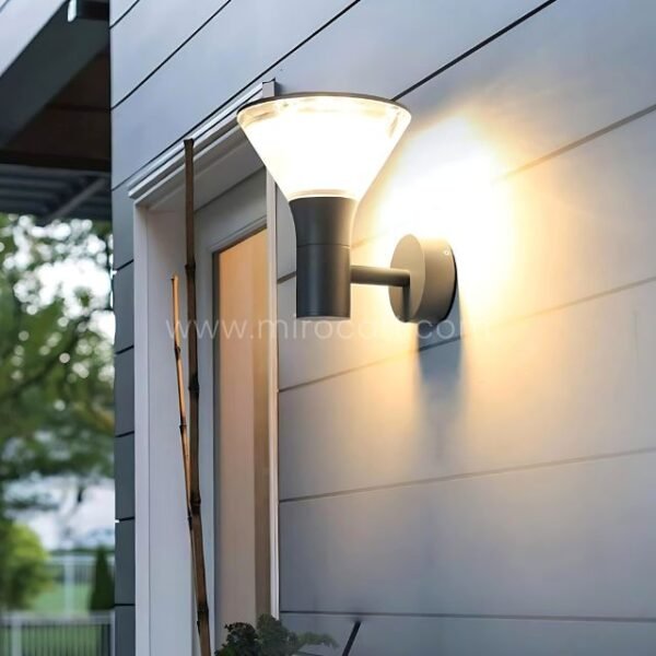 Modern outdoor wall light with black housing mounted on residential siding.