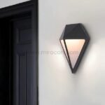 Diamond wall light mounted next to a dark door, providing warm, welcoming LED illumination in a minimalist entrance.