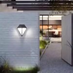 Sleek diamond wall light mounted on white brick, casting bright warm LED light on a contemporary outdoor walkway.