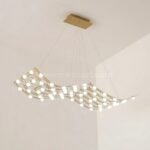 Serpentine flowing gold chandelier cascading in a bright, airy white room.